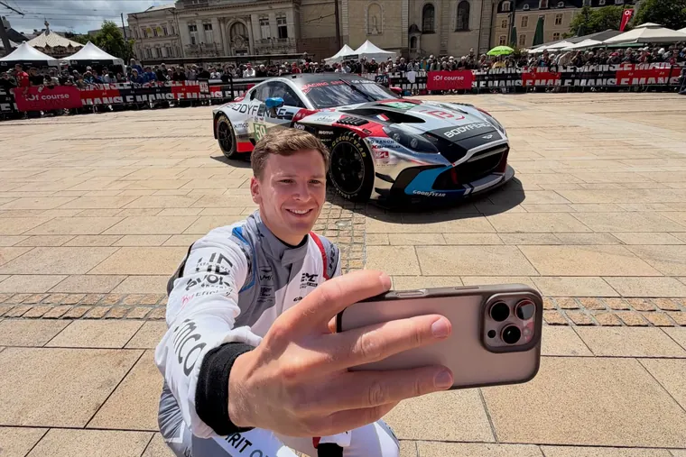 Selfie d'un pilote devant sa voiture, au cœur du Mans