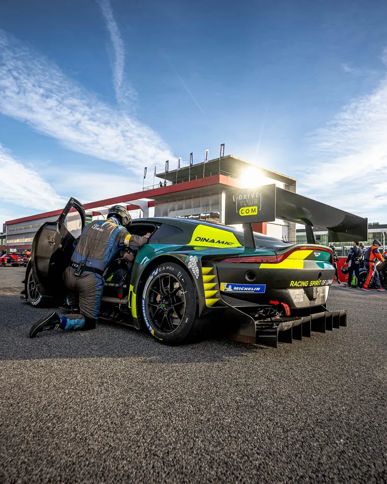 Aston Martin aux couleurs de ses partenaires, portière ouverte dans la voie des stands