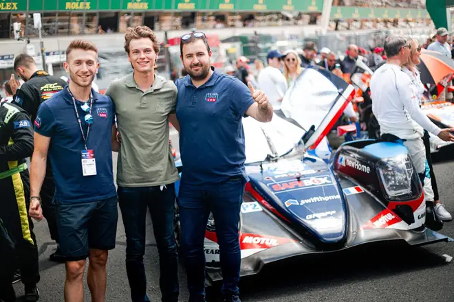 L'équipe et deux pilotes devant un prototype, sur la grille