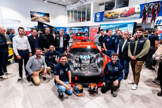 Photo de groupe autour d'une voiture de course, lors d'un événement partenaire